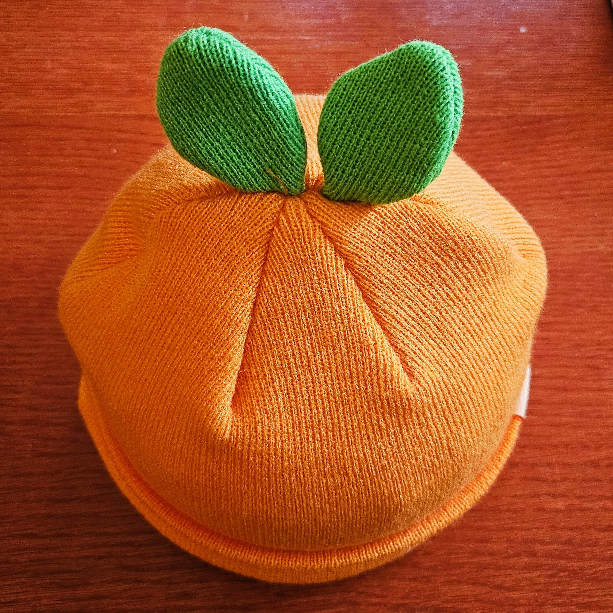 close up of the two green leaf sprouts at the top of the misomomo orange leaf beanie hat