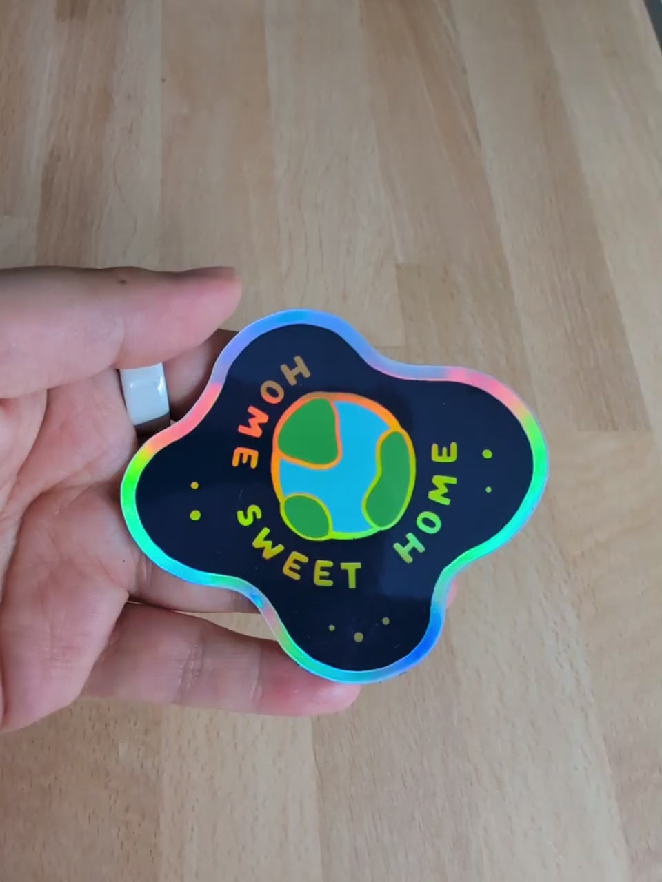 Video showcasing a vinyl holographic sticker featuring the planet earth floating in space, with the words Home Sweet Home