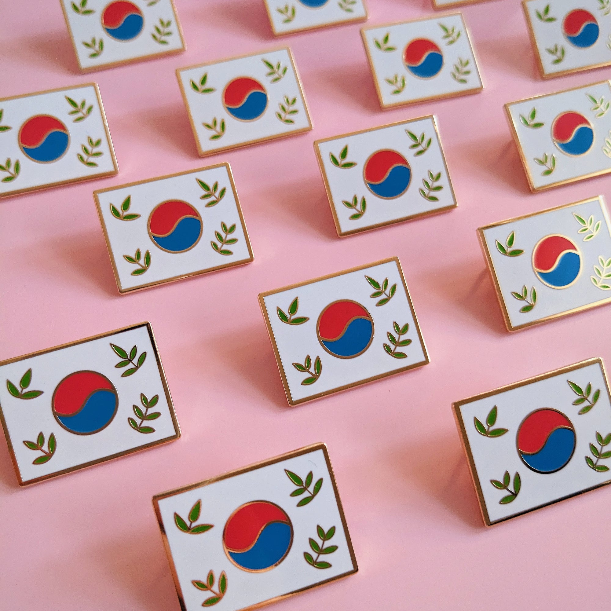 rows of mismomo korean flag enamel pins laid out on a pink background